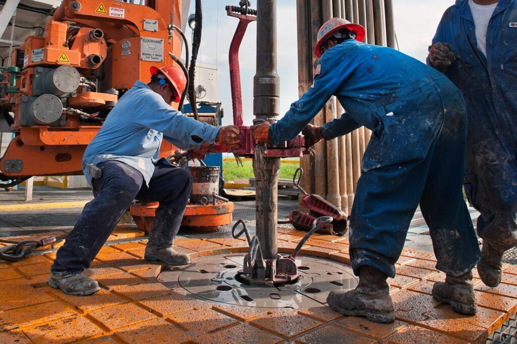 Oil rig workers operate a hydraulic wrench at a well site