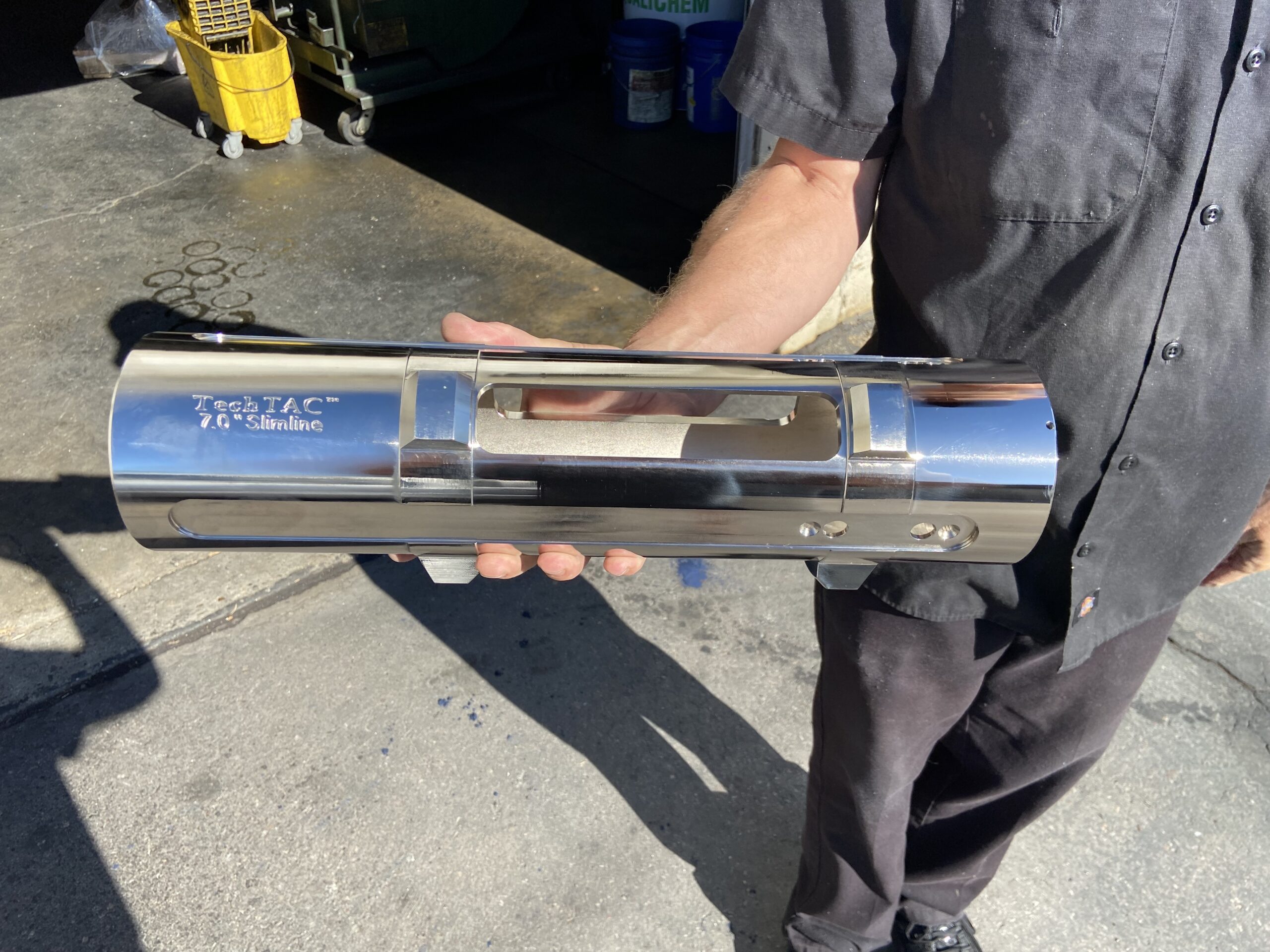 A TechTAC employee holding a nickel-coated Slimline TAC housing